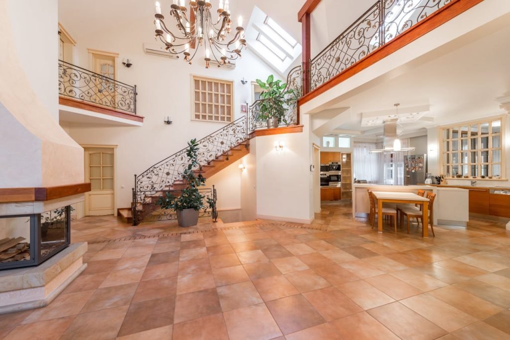 Elegant modern interior featuring a grand staircase, intricate chandelier, and open kitchen.